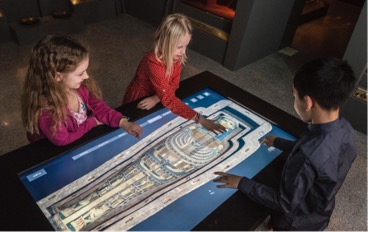 Figura 1. Giovani visitatori del Museo del Mediterraneo di Stoccolma utilizzano un tavolo di visualizzazione per esplorare i dettagli di un'antica mummia egizia.
